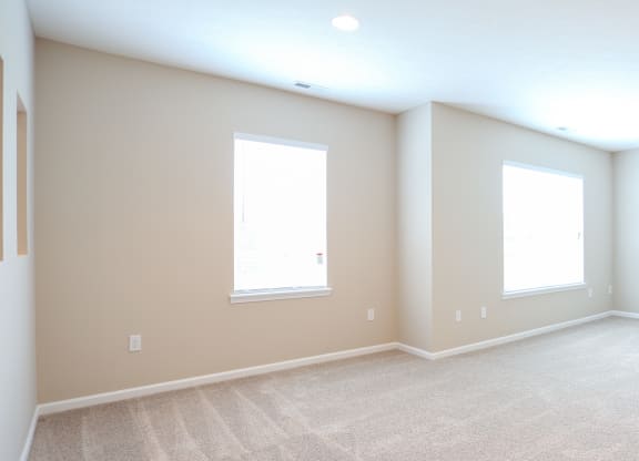 an empty room with two windows and a carpeted floor