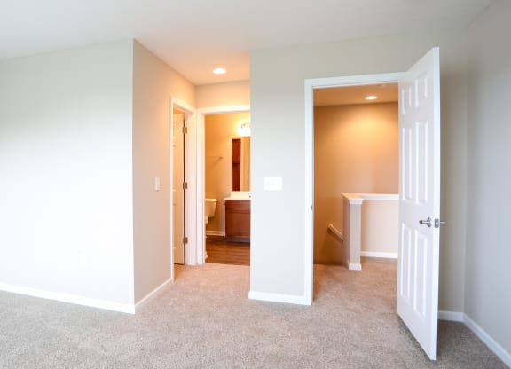 a bedroom with a door open to a bathroom and a closet