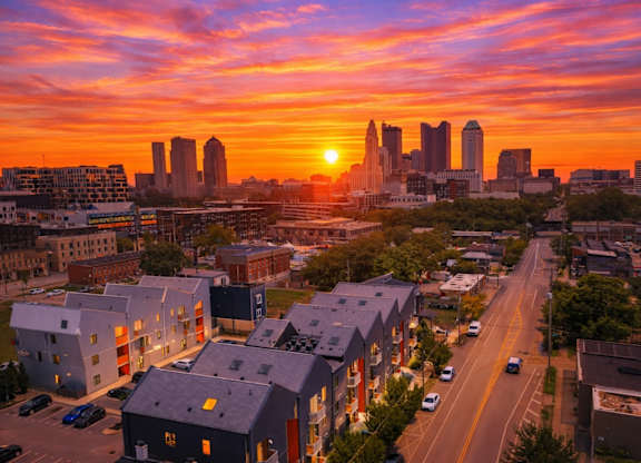 A cityscape at sunset with buildings and cars on the road.