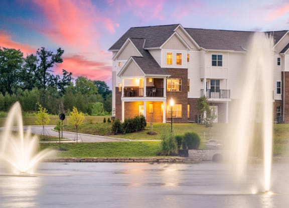 a fountain in front of a house at sunset