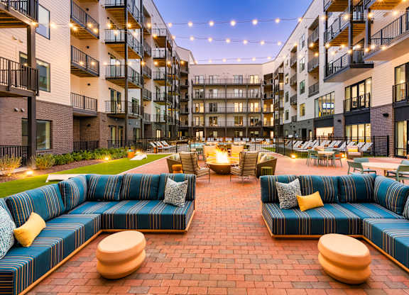 A large blue couch is in the middle of a courtyard surrounded by buildings.