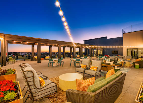A rooftop patio with a long row of chairs and tables.