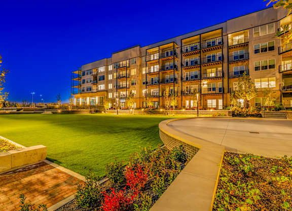A modern apartment complex with a well-lit courtyard and landscaping.