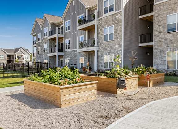 Apartment complex with a sandy courtyard and wooden planters.
