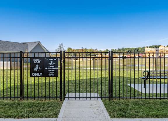 A sign at a dog park entrance indicates it is for small dogs only.