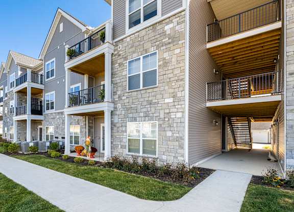 A modern apartment building with balconies and a walkway in front.