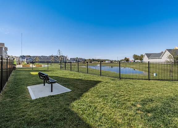 A park with a bench and a fence.