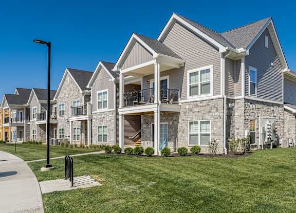 A large, modern house with a grey stone exterior and a balcony.