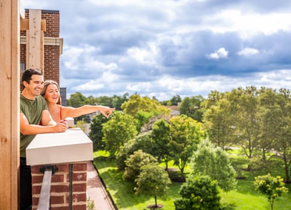 a couple standing on a balcony looking out at the view