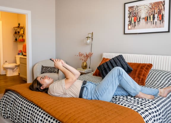 a woman laying on a bed with an orange blanket