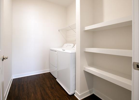 A white laundry basket sits on a shelf in a white room.