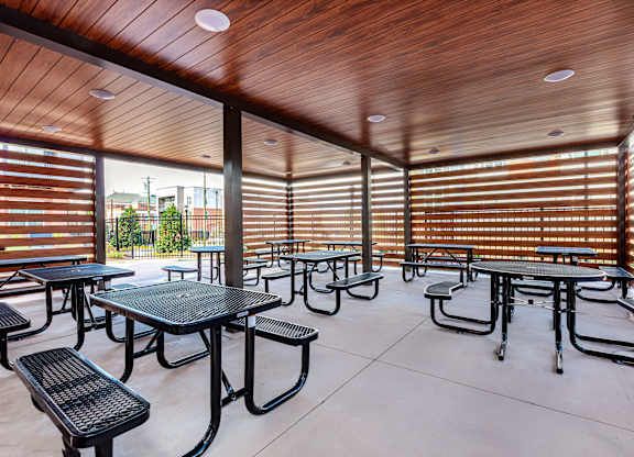 A patio with tables and chairs and a wooden ceiling.