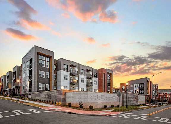 A modern apartment building is shown with a sunset in the background.