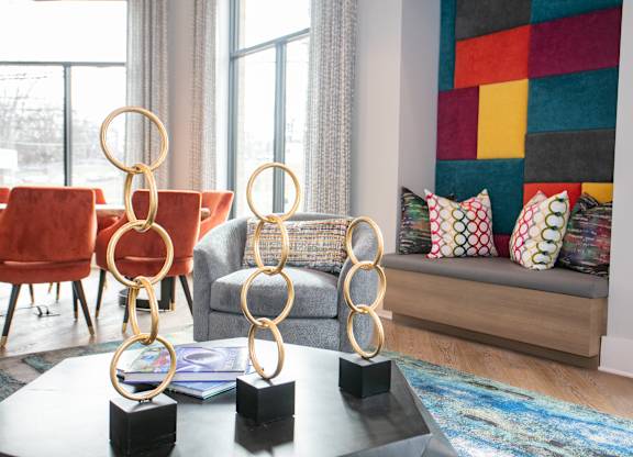 A living room with a grey couch, a red chair, and a coffee table with three golden rings on it.