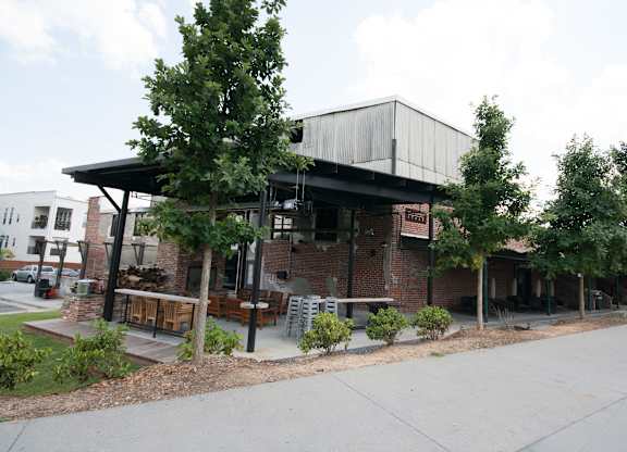 A building with a black roof and a sign that says "The Brewers" sits on a street corner.