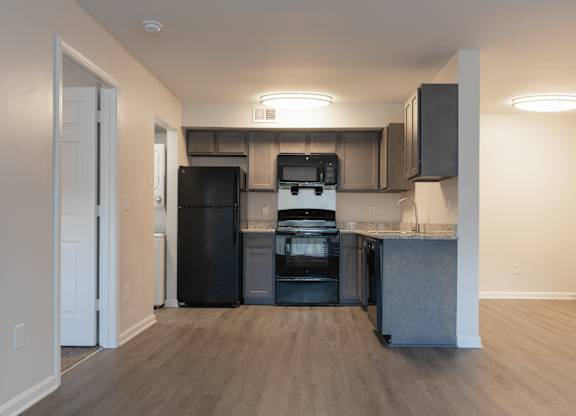 A kitchen with a black fridge, black oven, and black microwave.