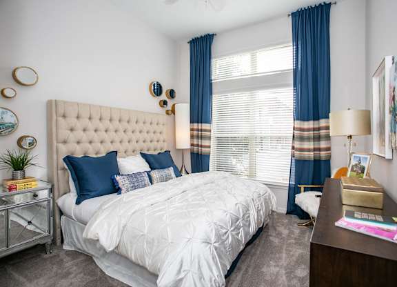 A bedroom with a large bed and a nightstand with a lamp.