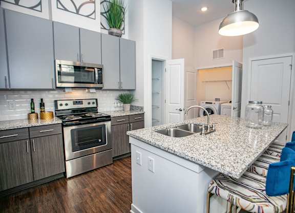 A kitchen with a granite countertop and stainless steel appliances.