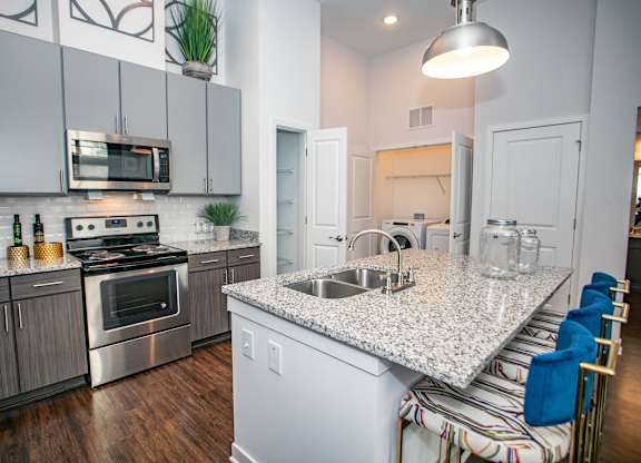 A kitchen with a granite countertop and stainless steel appliances.