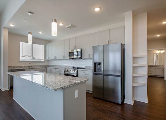 A modern kitchen with a granite countertop and stainless steel appliances.