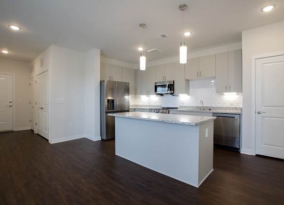 A modern kitchen with a large island and stainless steel appliances.