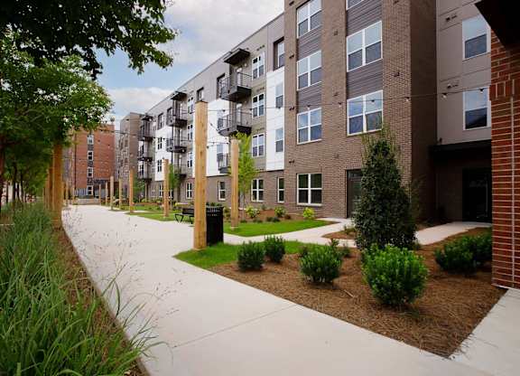 A long concrete walkway leads to a brick building with balconies.