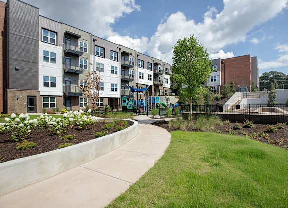 A modern apartment complex with a playground in the foreground.