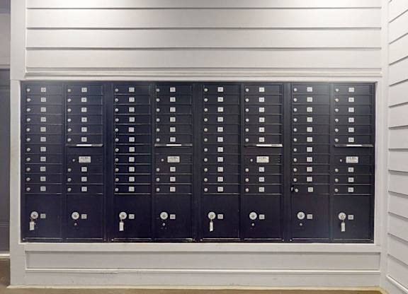 A row of black mailboxes are lined up on a wall.