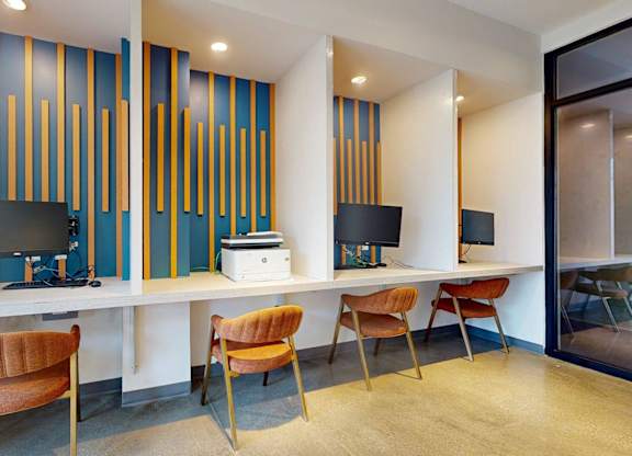 A room with a desk, chairs and a computer.