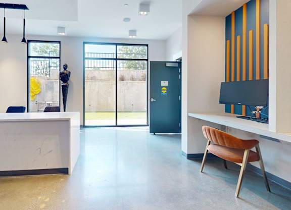 A reception area with a white desk and a brown chair.