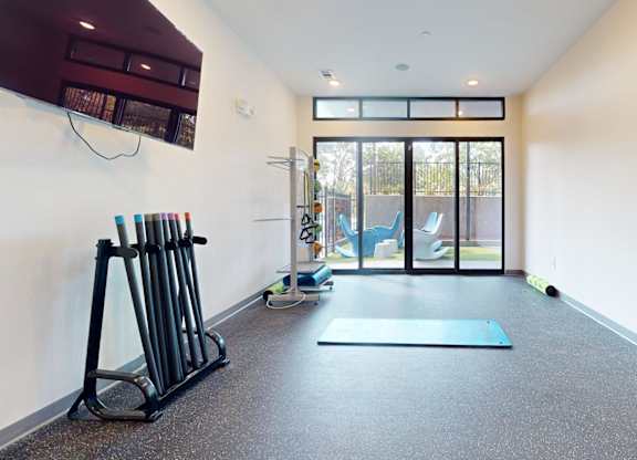 A gym with a blue mat and a row of dumbbells.