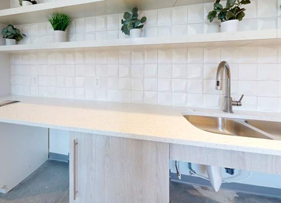 A white kitchen with a sink and a cabinet.