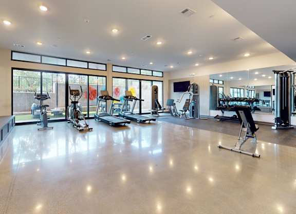 A spacious gym with a variety of equipment and a large mirror on the wall.