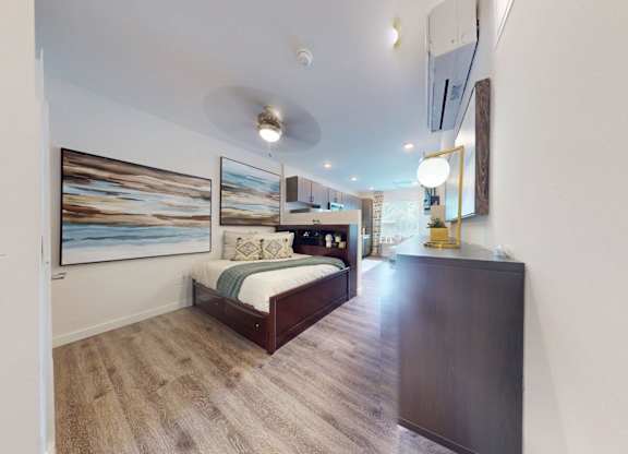 A bedroom with a bed, a painting on the wall, and a mirror on the wall.