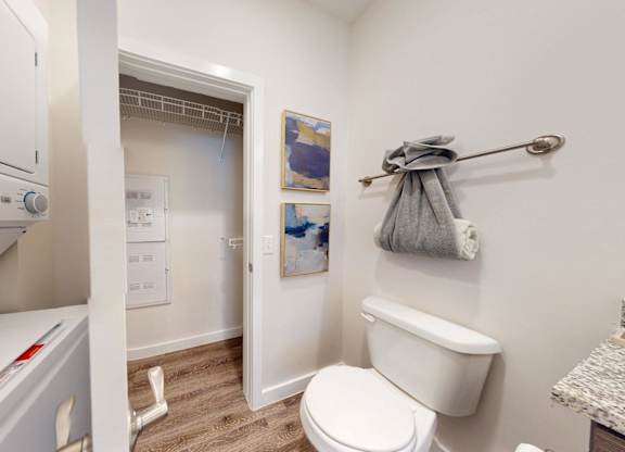 A white dryer is on the left of a white toilet in a small bathroom.