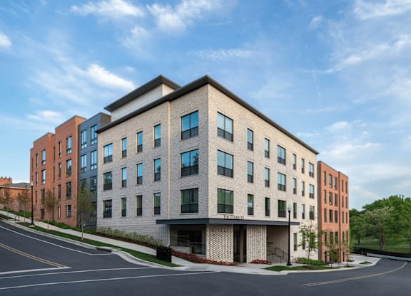 A modern multi-story building with a parking lot in front.