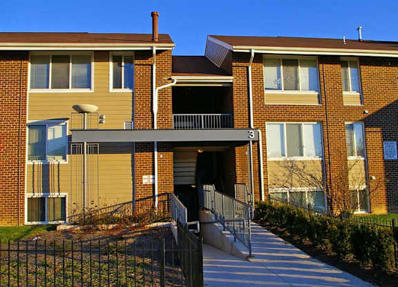 A brick apartment building with a black gate in front.