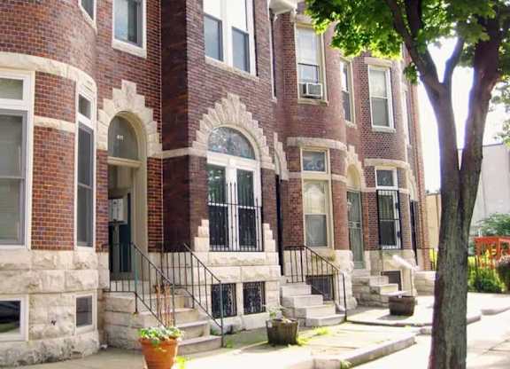 A red brick building with a black iron railing on the steps.