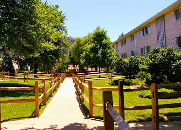 A pathway with wooden fences on either side leads through a grassy area.