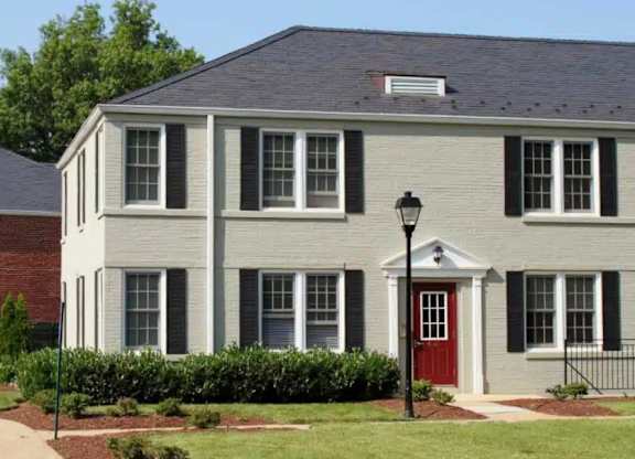 A white house with a red door and black shutters.