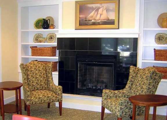 A living room with a fireplace and two chairs.