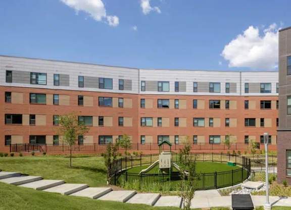 A large red brick building with a playground in front.