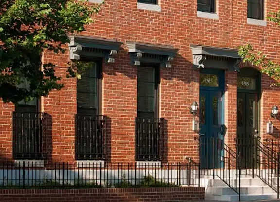 A red brick building with a green door and black iron fencing.