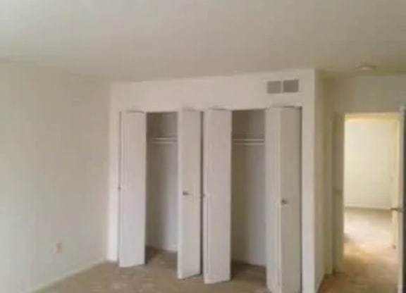 Three white closet doors are open in a room.