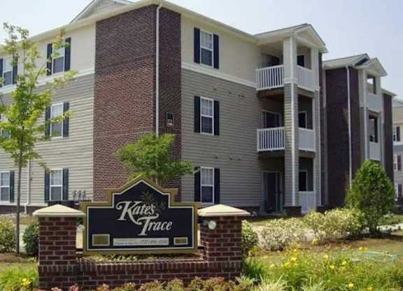 A brick building with a sign that says Kates Trace in front of it.