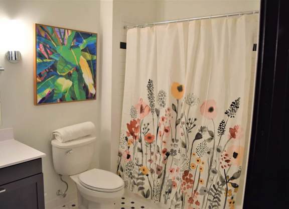 A bathroom with a toilet, sink, and a shower curtain with a floral pattern.