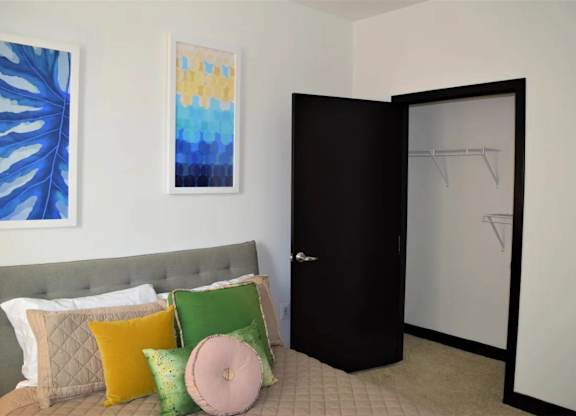A bed with a grey headboard and a pillow with a pink pillow case on it.