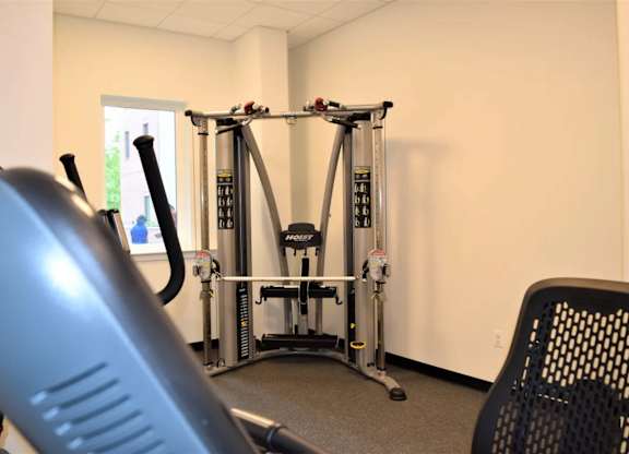 A gym with a weight machine and a chair.