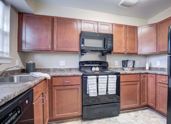 A kitchen with brown cabinets and a black refrigerator.