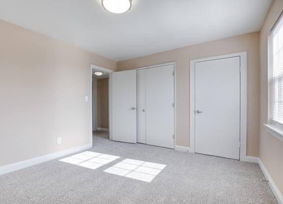A room with three white doors and a carpeted floor.
